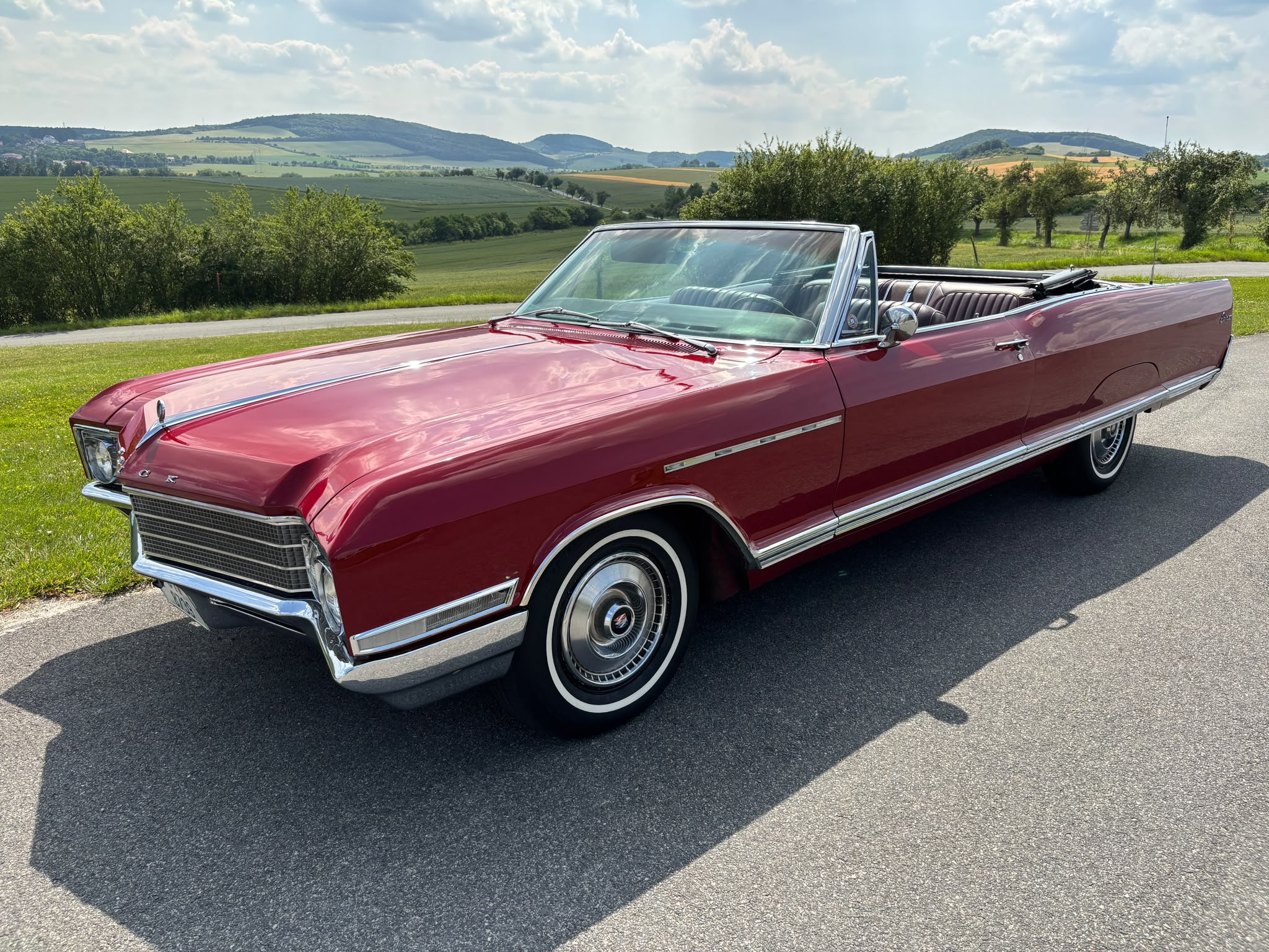 Červený Buick Electra 1966 s otvorenou strechou v slnečnej krajine